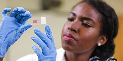 a woman peers at a microscope slide